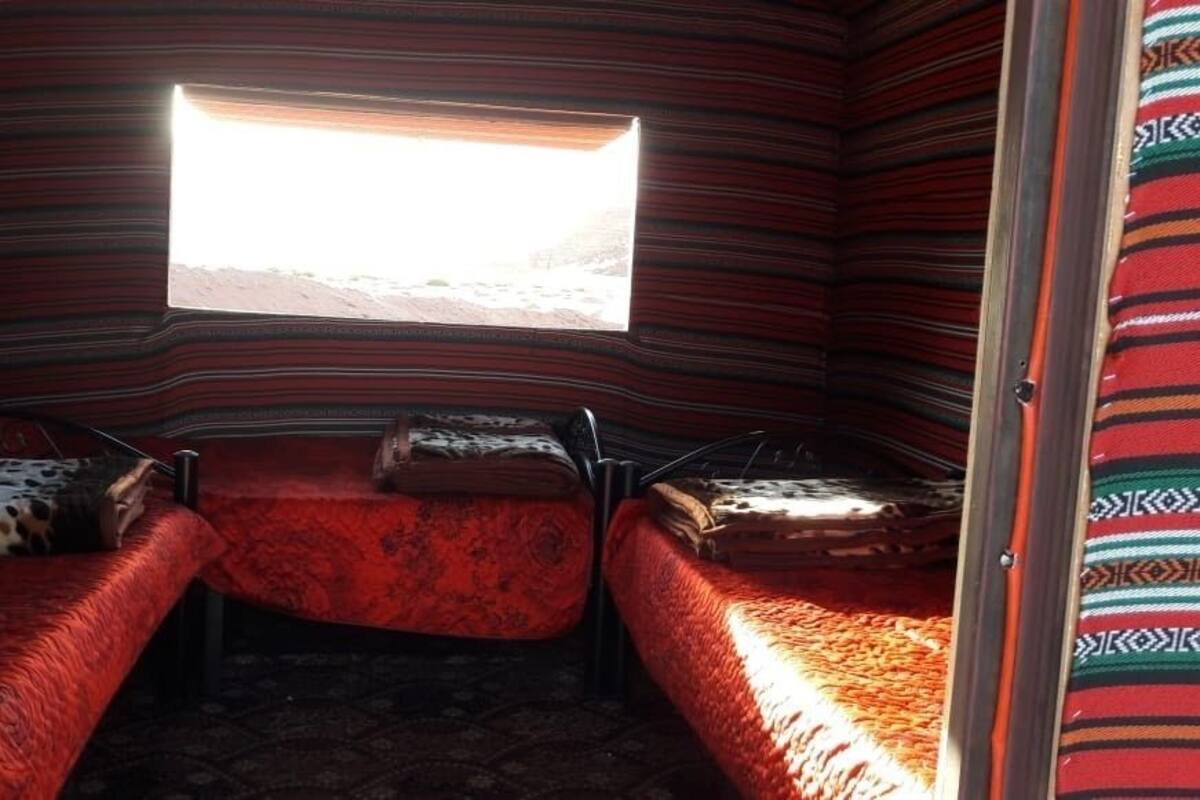 Un petit espace clos comprenant deux lits, une fenêtre et un mur décoré de motifs.