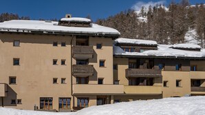 Ein mehrstöckiges Hotel mit Balkonen und einem mit Schnee bedeckten Dach.