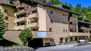 Ein mehrstöckiges Hotel mit Balkonen, einer Skiliftanlage und Bergblick.