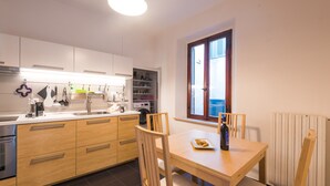 A modern kitchen with wooden cabinets, a dining table, and chairs. - Your home in Trequanda (Trequanda)