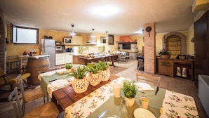 A spacious kitchen with a dining area, featuring a brick fireplace, wooden cabinets, and a large dining table set for six. - B&B Al Sentiero (Caprino Veronese)