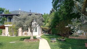 A well-maintained garden with a pathway leading to a house. - B&B Al Sentiero (Caprino Veronese)