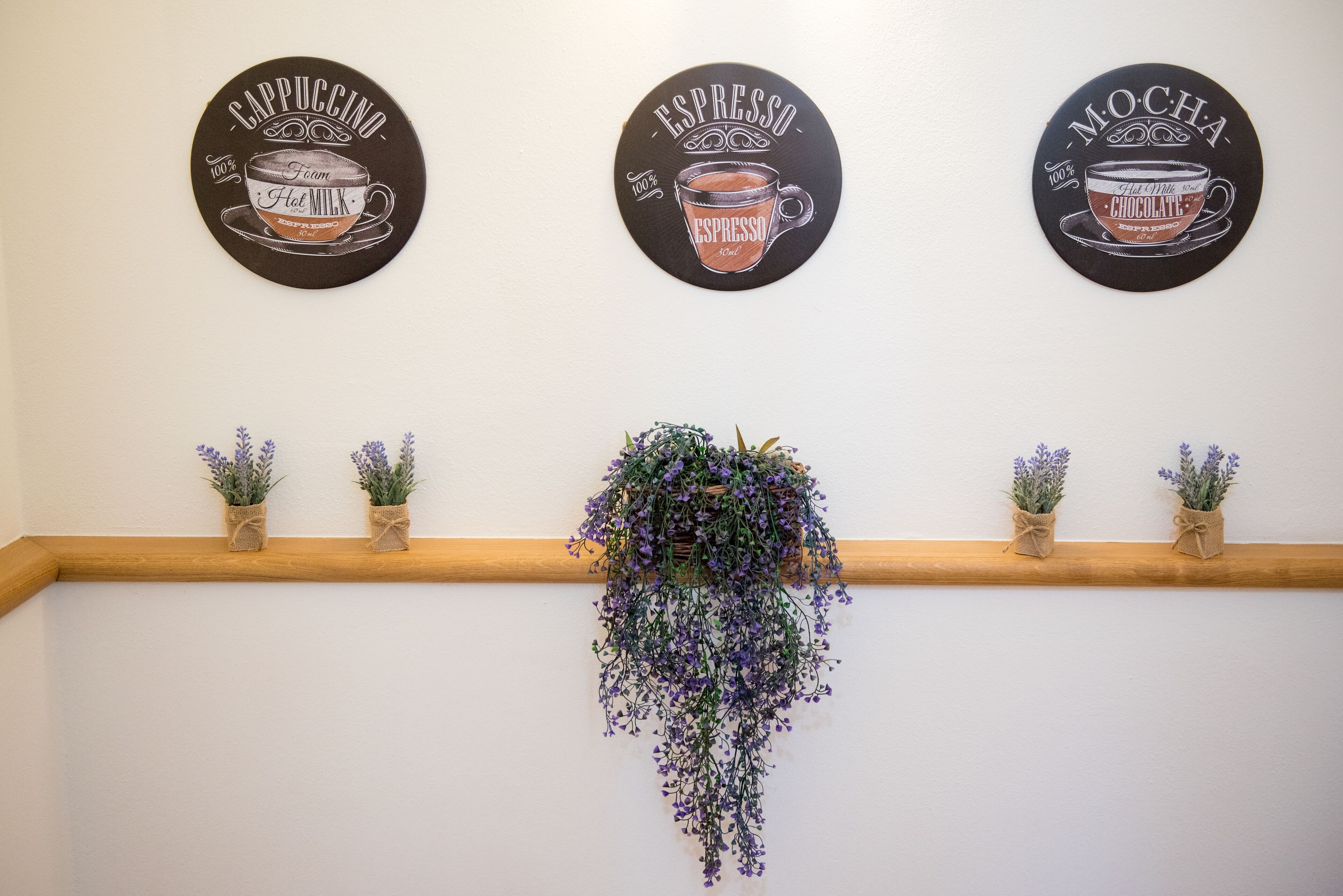 Tre väggdekaler med kaffetema och en hängande blomsterdekoration.