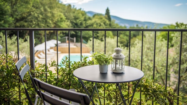 A balcony with a round table, a potted plant, and a lantern. - B&B Al Sentiero (Caprino Veronese)