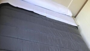 A bed with a grey mattress and white bedding. - Camping El Tormes (Alba de Tormes)