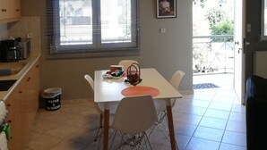 A dining area with a table, chairs, and a hanging light fixture.