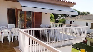 Un balcon avec une balustrade blanche, un coin repas avec des chaises blanches et un petit espace piscine avec des chaises jaunes.