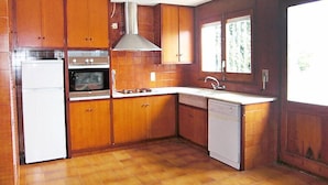 Une cuisine avec des meubles de rangement en bois, un réfrigérateur, un four, une cuisinière, un évier et un lave-vaisselle.