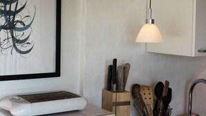 A kitchen with a white microwave, a hanging pendant light, and a framed abstract artwork on the wall. - Spangsgaard bed and breakfast (Odense)