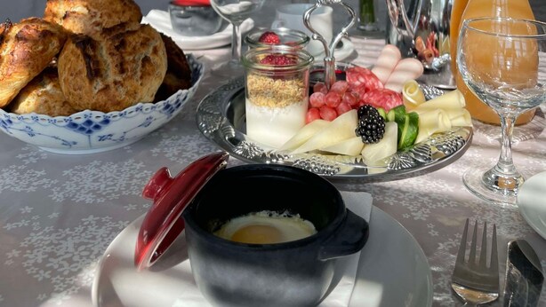 A breakfast table with pastries, a fruit and yogurt parfait, a coffee pot, and a pitcher of orange juice. - Spangsgaard bed and breakfast (Odense)