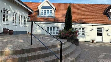 A building with a red-tiled roof, a staircase leading to a door, and a clear blue sky.