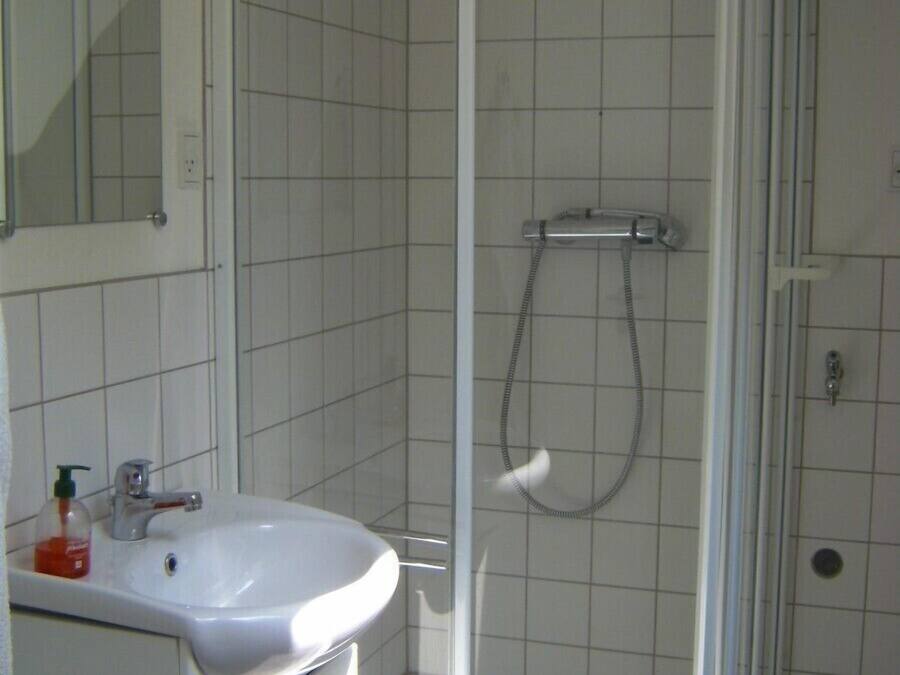 A bathroom with a white sink, a mirror, and a glass-enclosed shower.