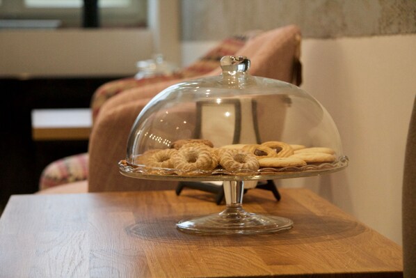 A wooden table with a glass-covered dessert stand holding pastries.