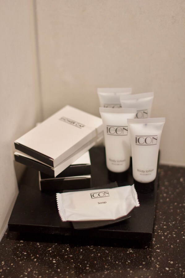 A black tray with ICON body lotion tubes, a soap bar, and a box on a speckled countertop. - Chevron Design Hotel Prague (Prague)