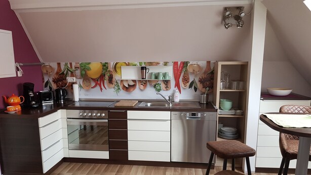 Una cucina moderna con forno a incasso, lavastoviglie e un'area pranzo con due sgabelli.