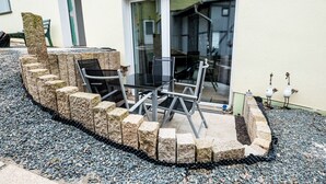 A patio area with a stone border, a table, and chairs.