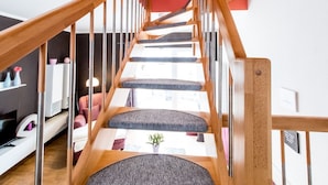 A wooden staircase with a red wall and a small window at the top.