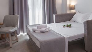 Una habitación de hotel moderna con una cama, una silla y una mesita de noche.