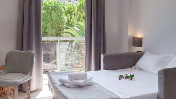 Habitación de hotel moderna con cama, una silla, una mesita de noche y vistas a zonas verdes.