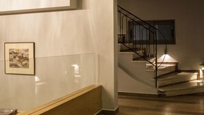 Un interior moderno con un mostrador de recepción de madera, una escalera con barandilla metálica y un cuadro enmarcado en la pared.