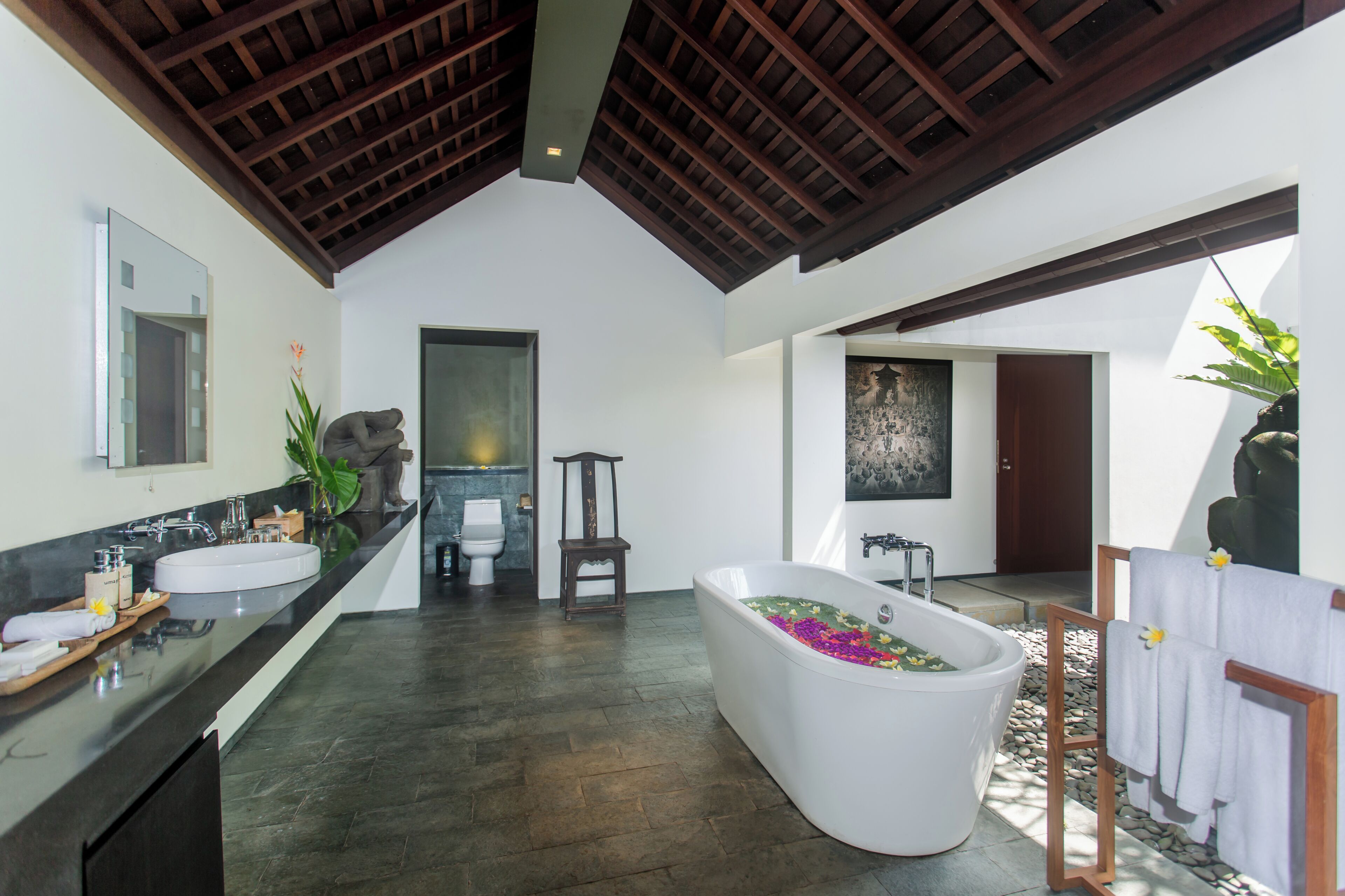 A modern bathroom with a freestanding bathtub, a large mirror, and a wooden ceiling.