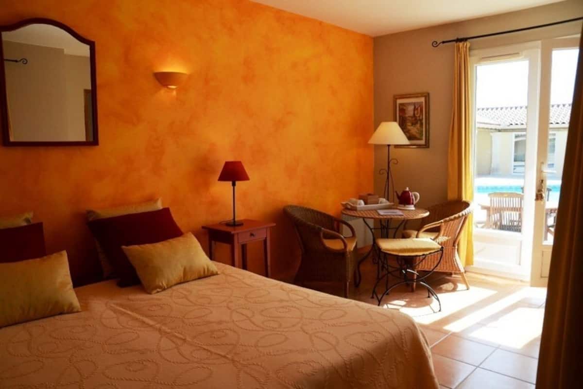 A hotel room with a bed, a desk, a chair, and a view of the outside.