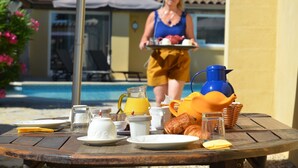 A breakfast table with plates, cups, and a pitcher of orange juice. - Villa des Cammaous (Vacquieres)