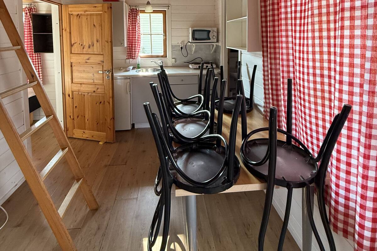 Interior de madera con comedor, cocina y un dormitorio en entrepiso.