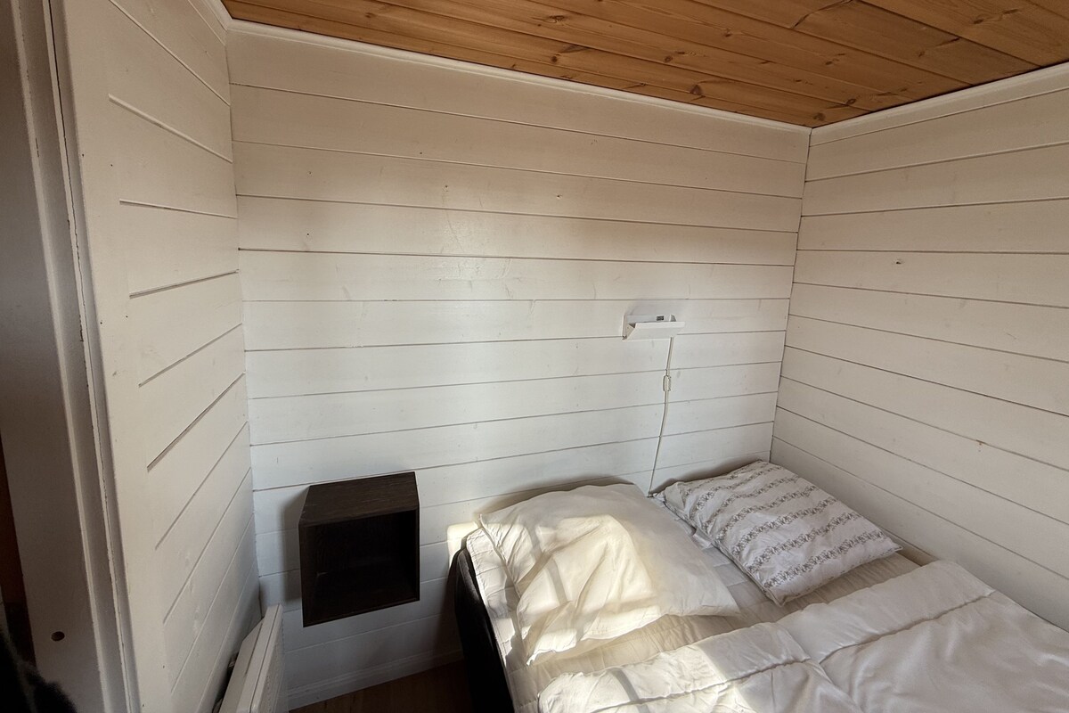 Une petite chambre avec un lit simple, aux murs blancs et au plafond en pente.
