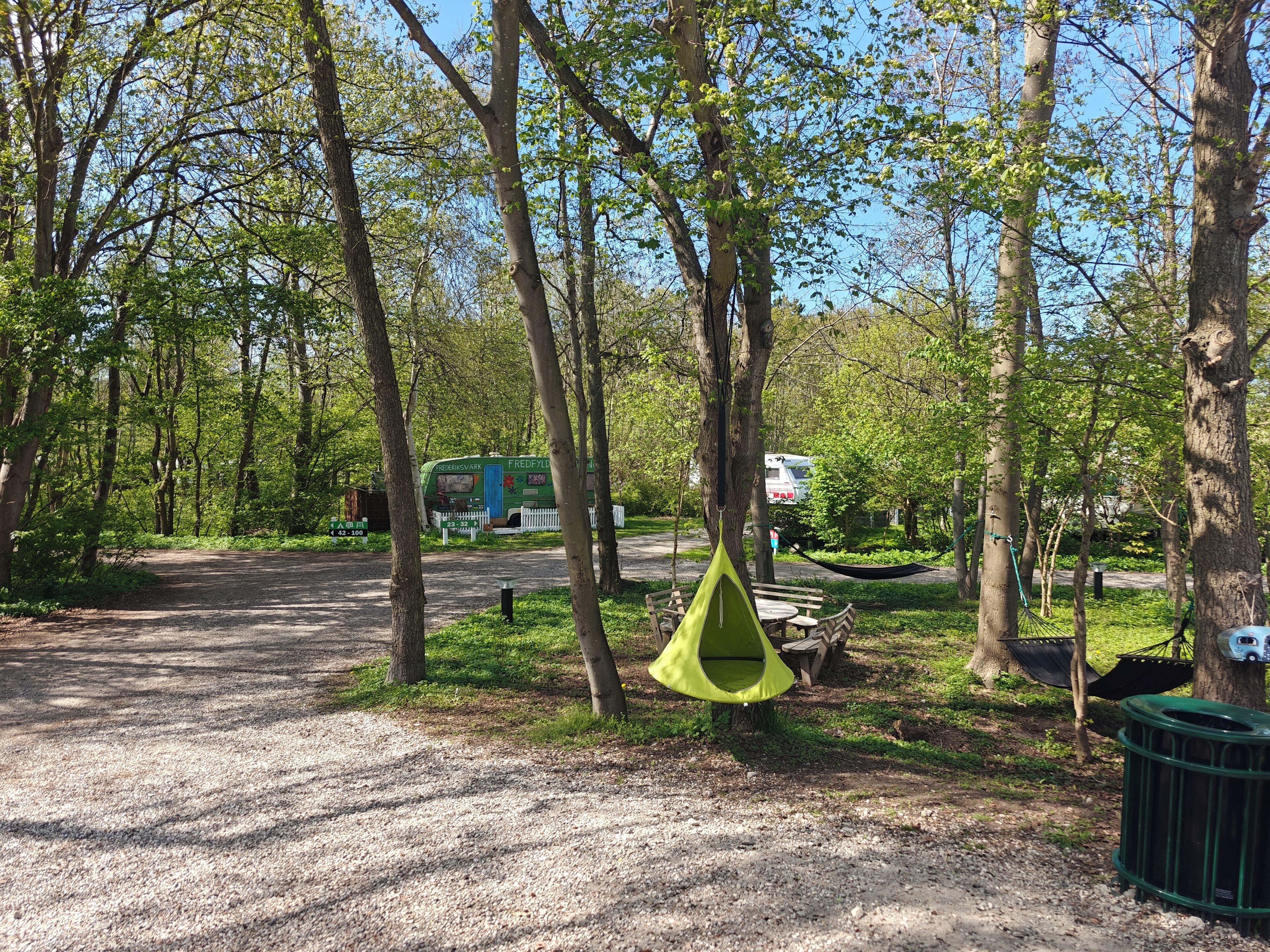 A campsite with a dirt path, picnic tables, and a hammock.