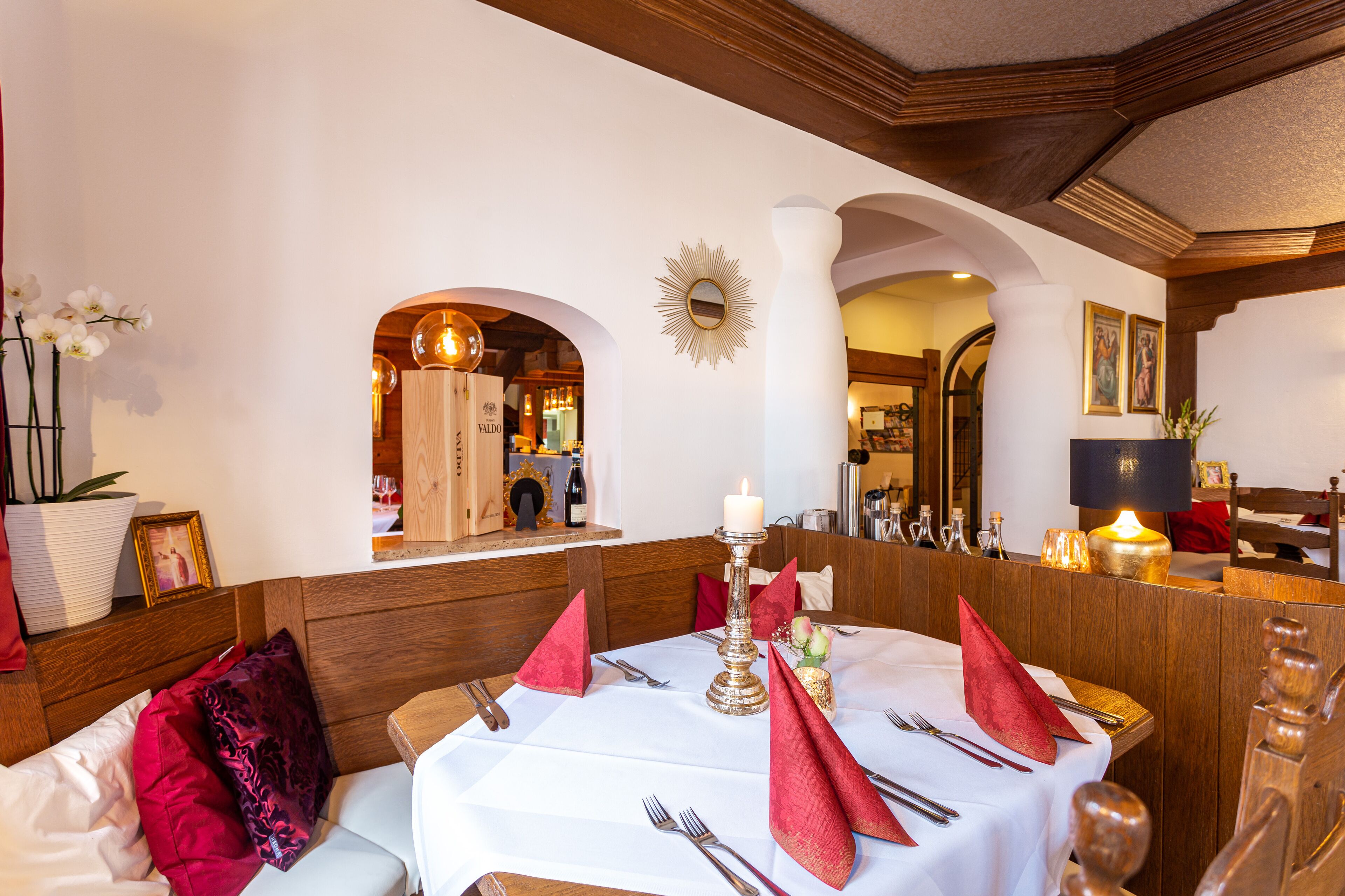 A dining area with a round table set for four, a candle centerpiece, and red napkins.