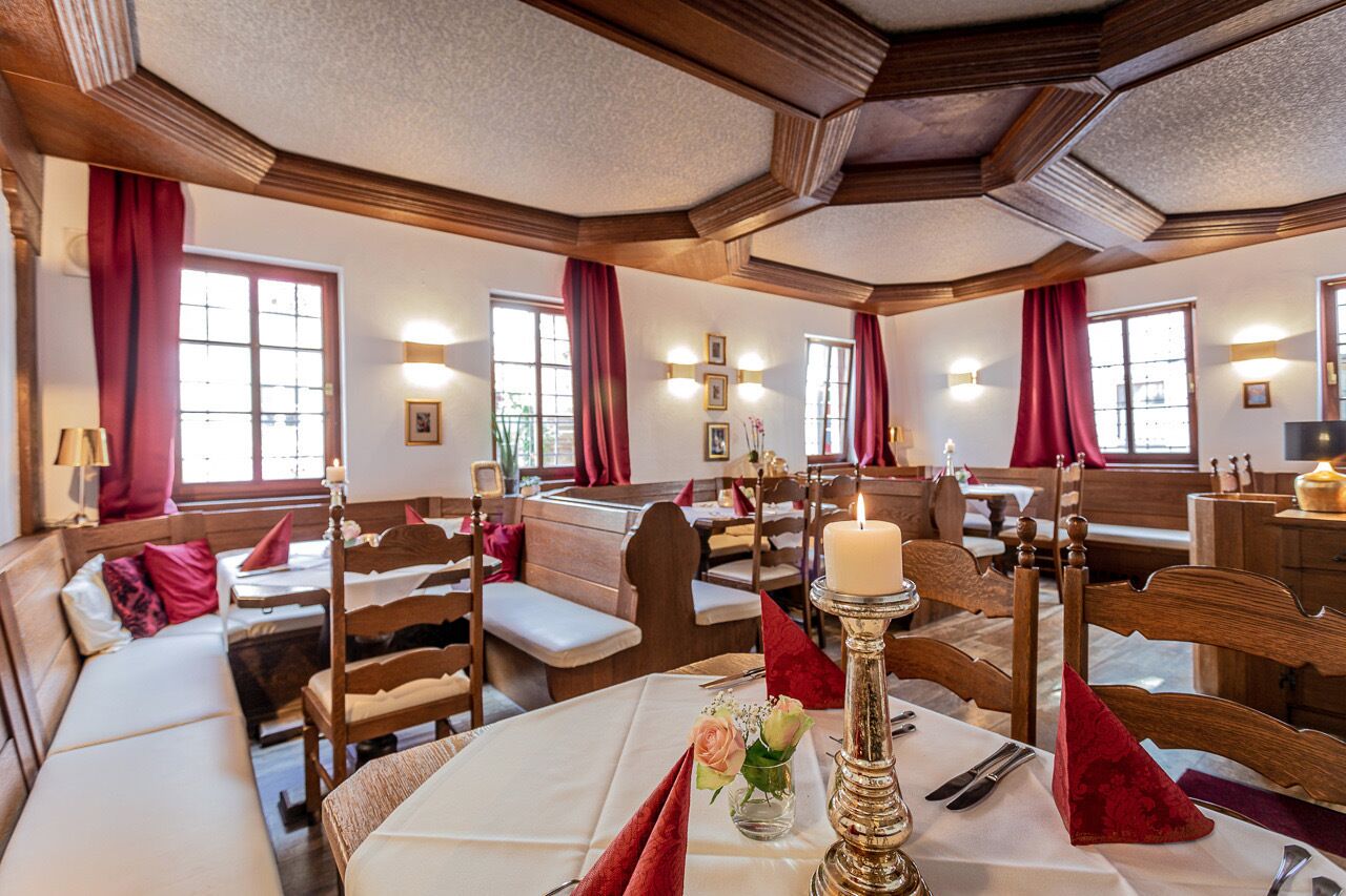 Un restaurant chaleureux, avec des meubles en bois, des rideaux rouges et des tables éclairées à la bougie.