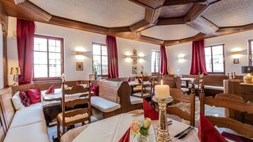 A cozy restaurant with wooden furniture, red curtains, and candlelit tables.