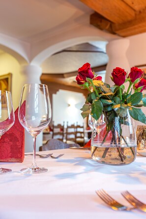 A table set with wine glasses and a vase of roses.