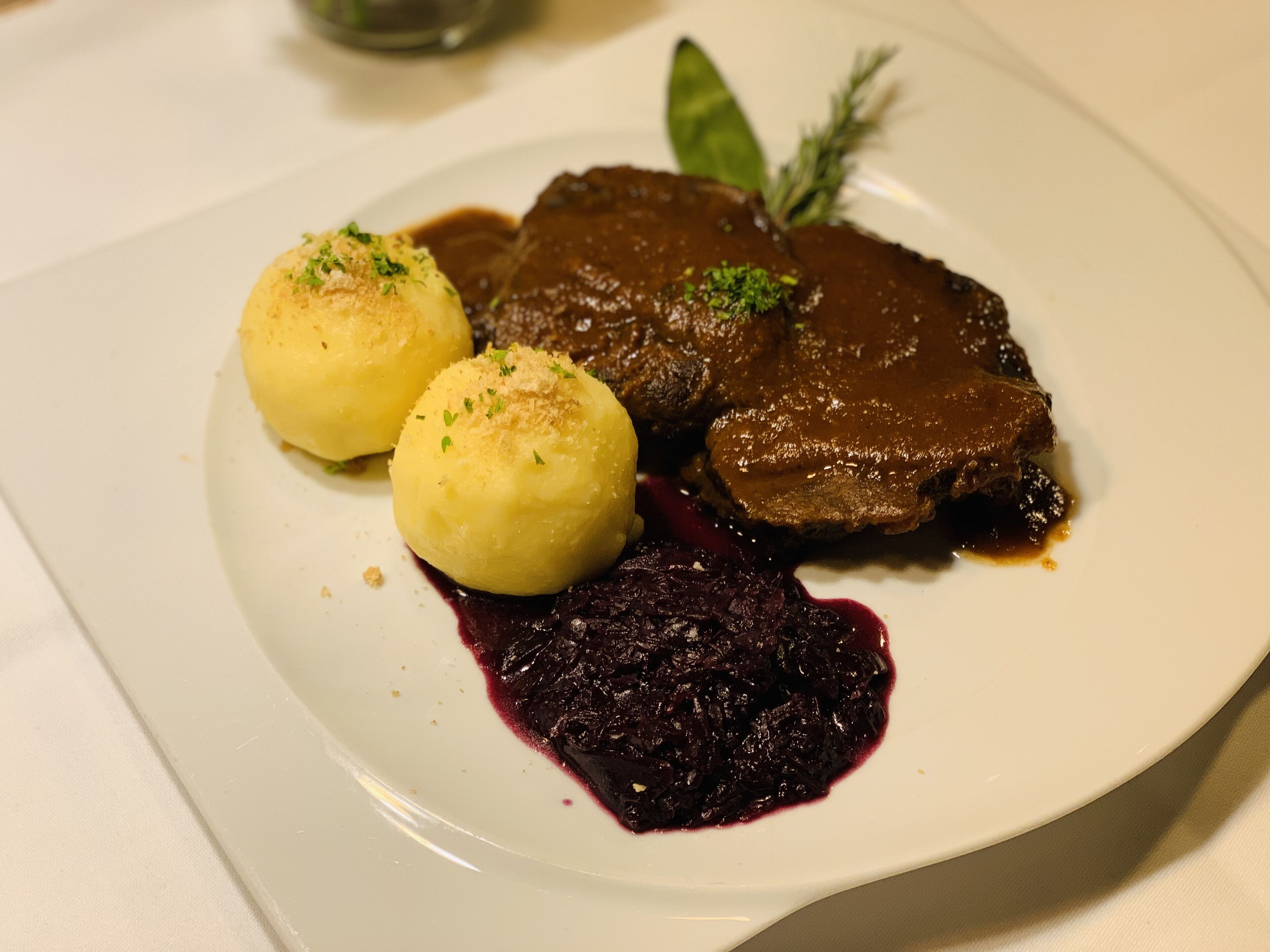 Une assiette contenant un plat de viande, deux boulettes et une sauce aux fruits rouges.