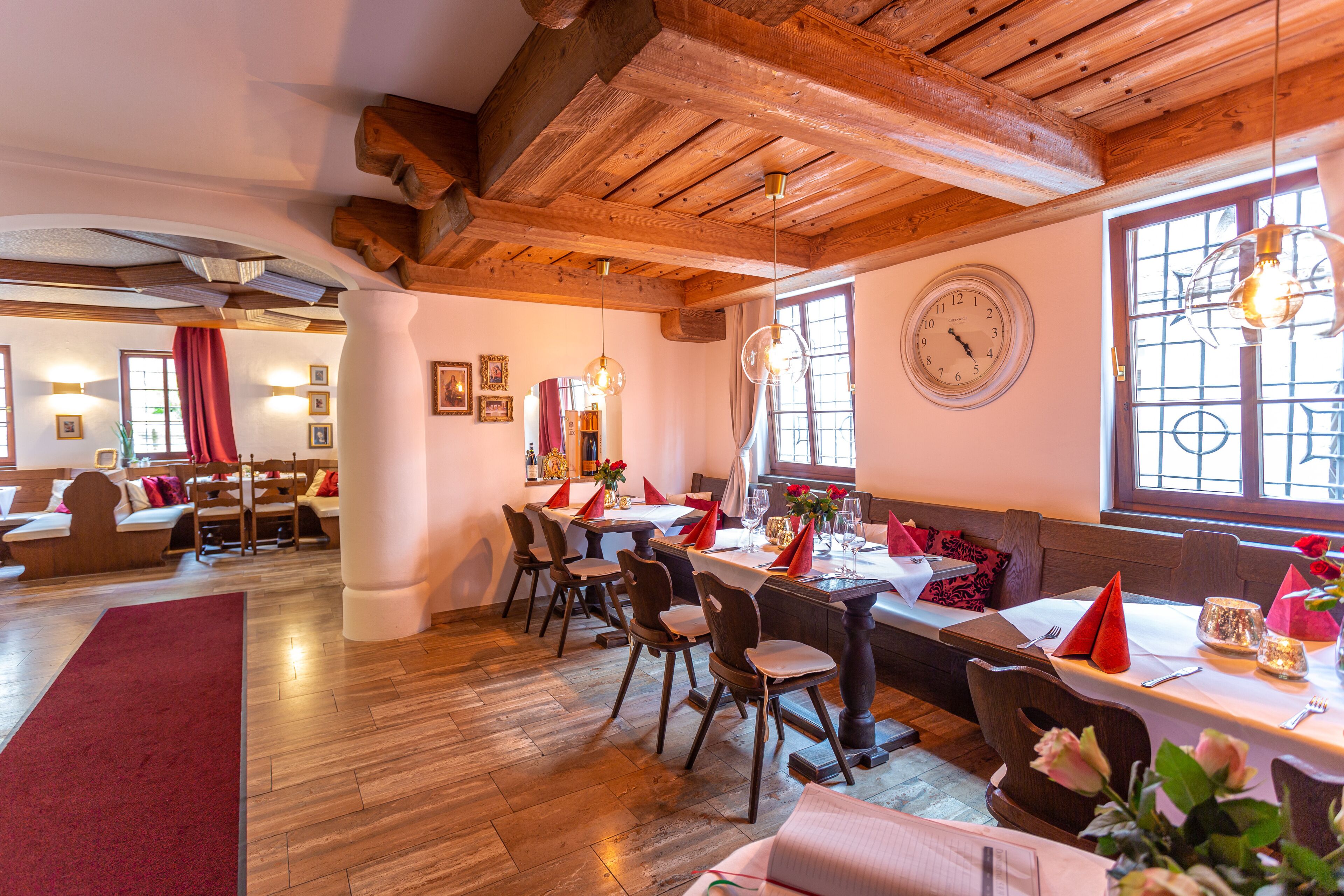 Un restaurante con vigas de madera, un reloj grande y una zona de estar acogedora.