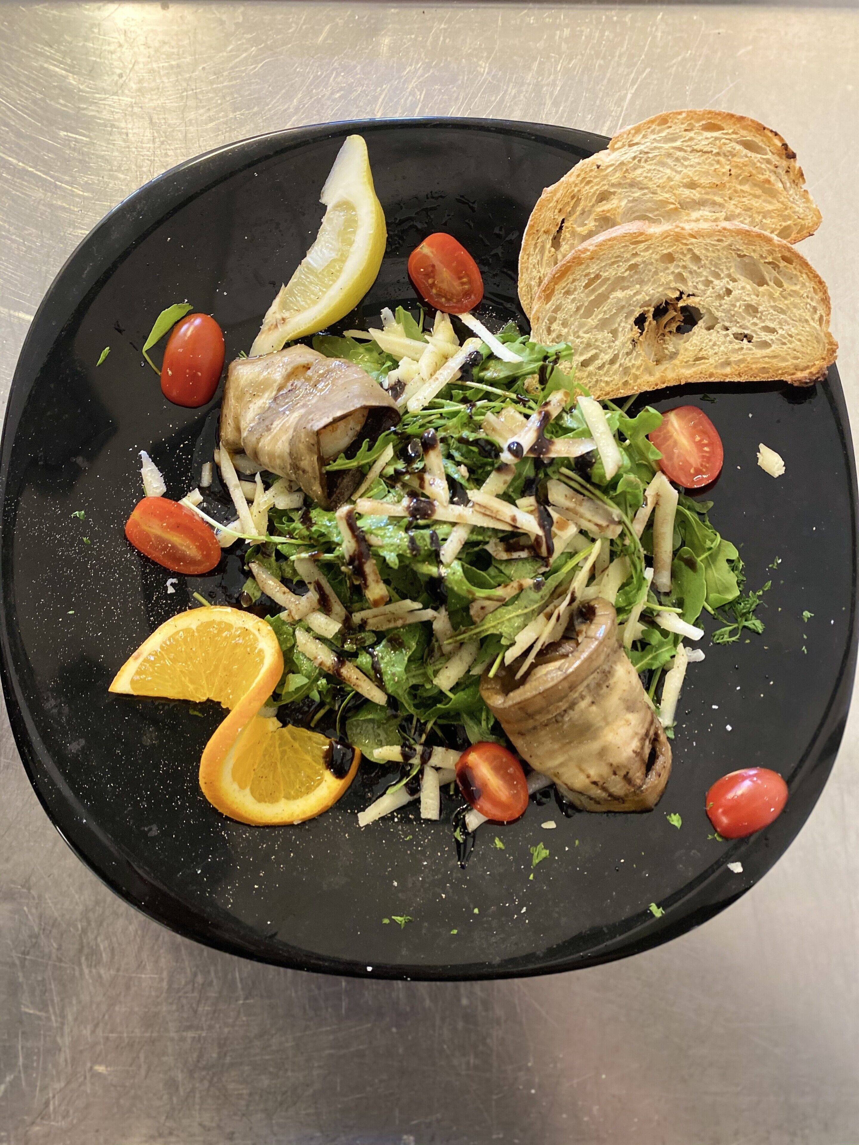 Un plato de comida con ensalada, pollo a la parrilla y pan.