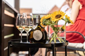 A table with wine glasses, a bottle, and a vase with sunflowers.