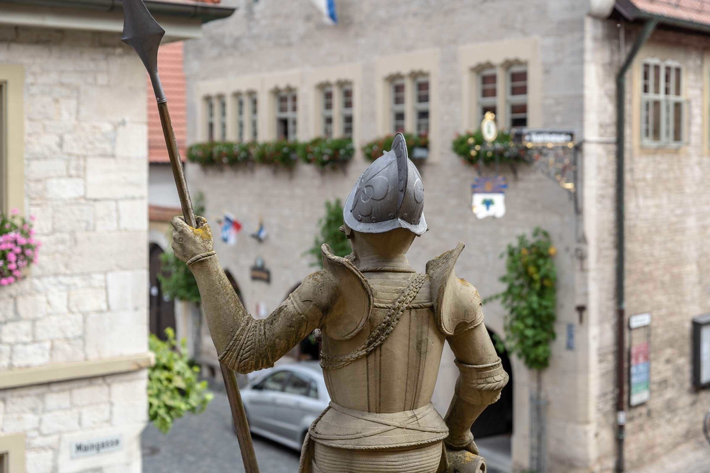 A statue of a knight holding a spear in a town square.