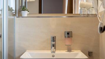 A modern bathroom with a white sink, chrome faucet, and a glass soap dispenser.