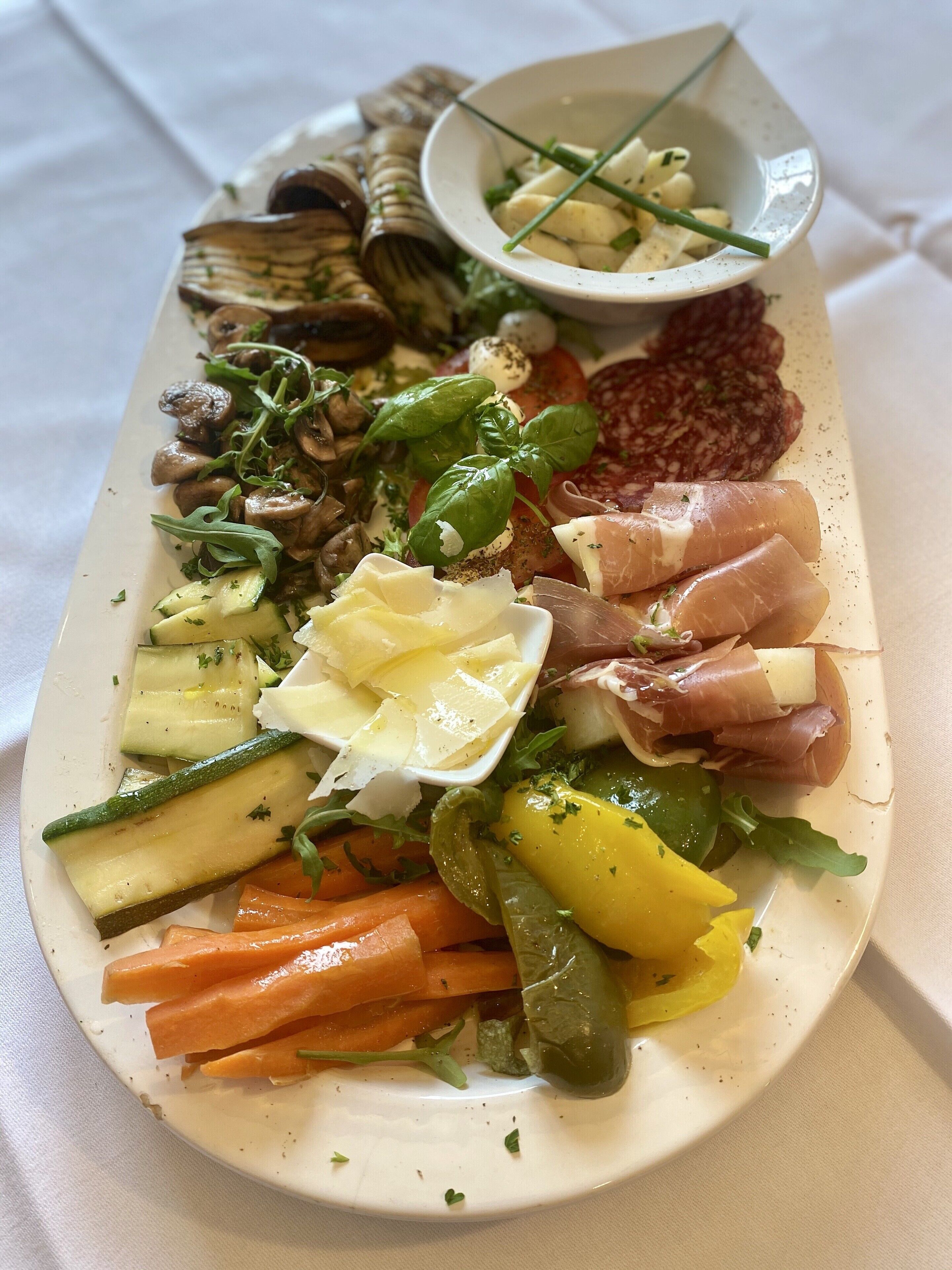 A charcuterie board with various meats, cheeses, and vegetables.