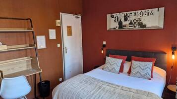 Ein Schlafzimmer mit einem Bett, einem Schreibtisch, einem Stuhl und einer Tür.