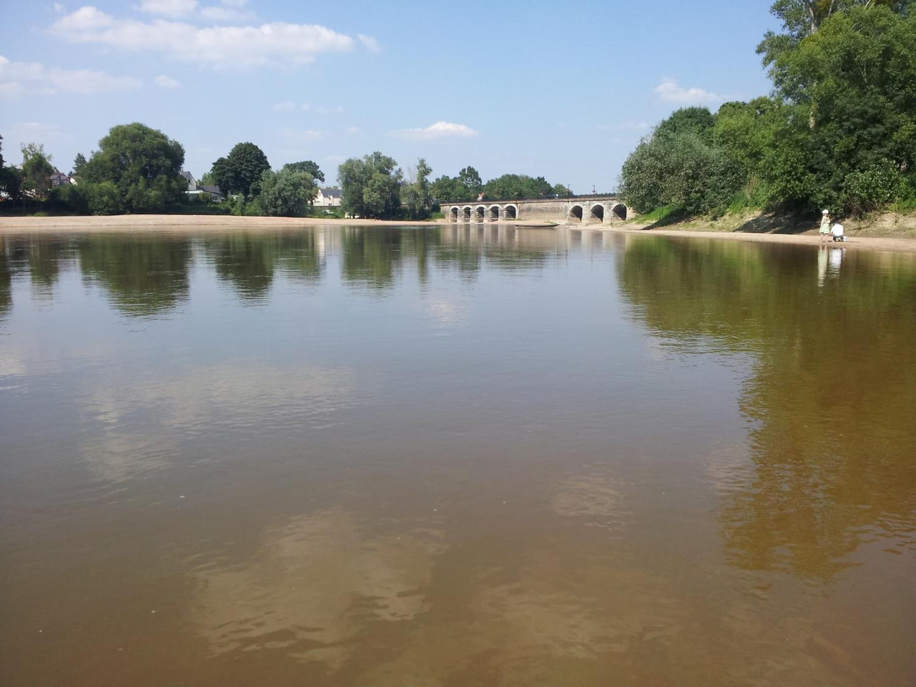 A calm river with a bridge in the background.