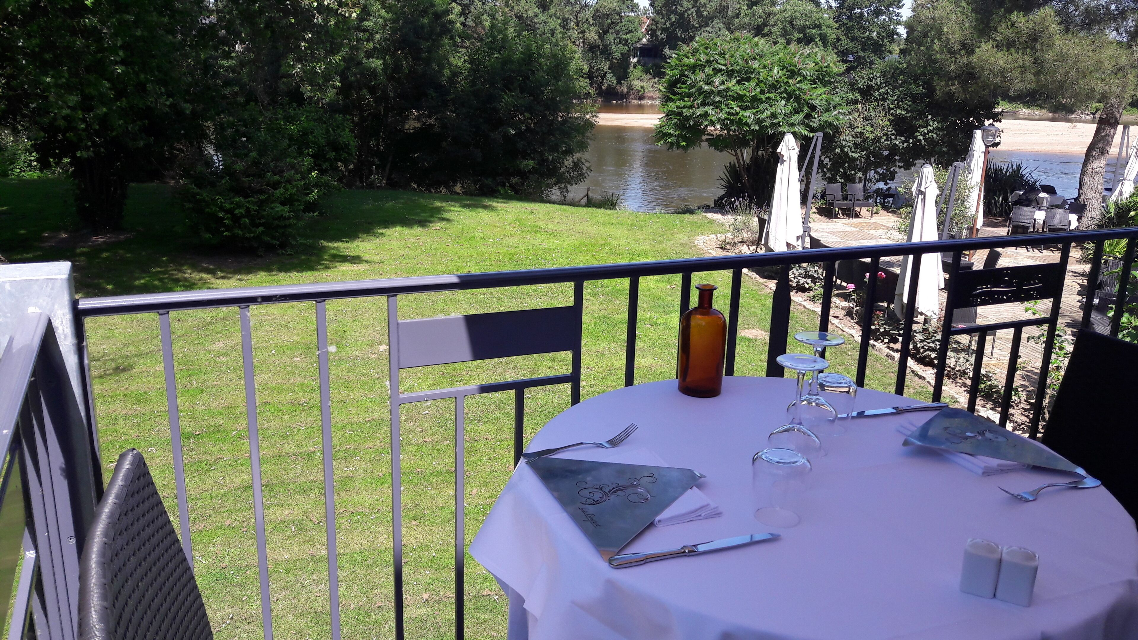 Mesa lista para comer con vista a un río y vegetación.