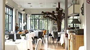 Un espace repas comprenant plusieurs tables et chaises, de grandes fenêtres et un plafond doté d’un éclairage encastré.
