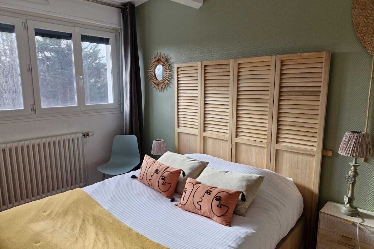 Un dormitorio con cama, una silla, una mesita de noche y una ventana.