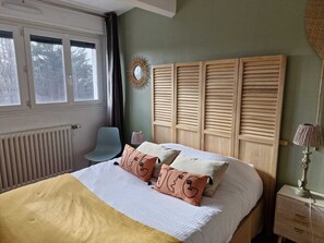 Ein Schlafzimmer mit Bett, Stuhl, Nachttisch und Fenster.