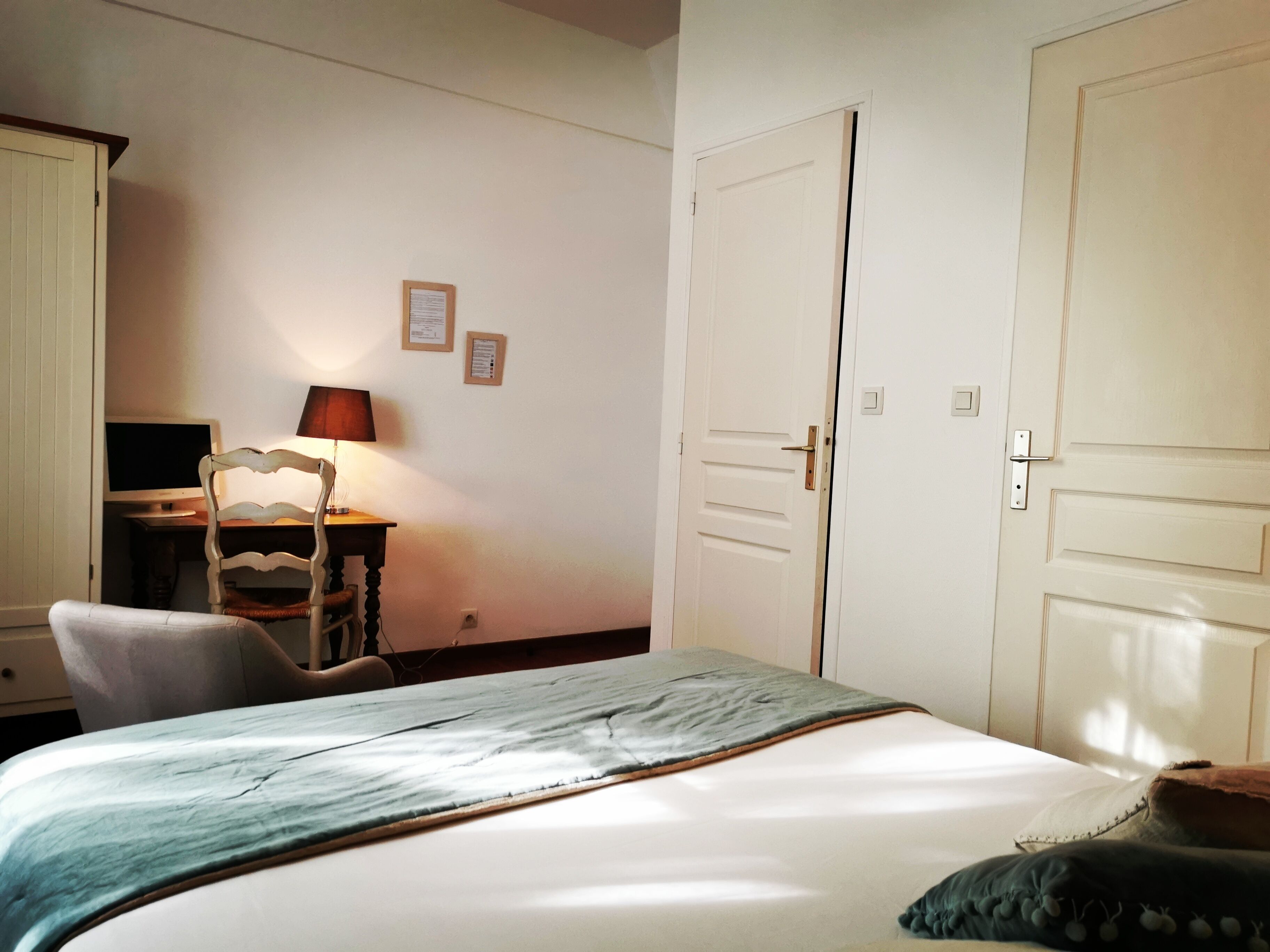 Una camera da letto con un letto, una scrivania con un computer, una sedia e due porte.