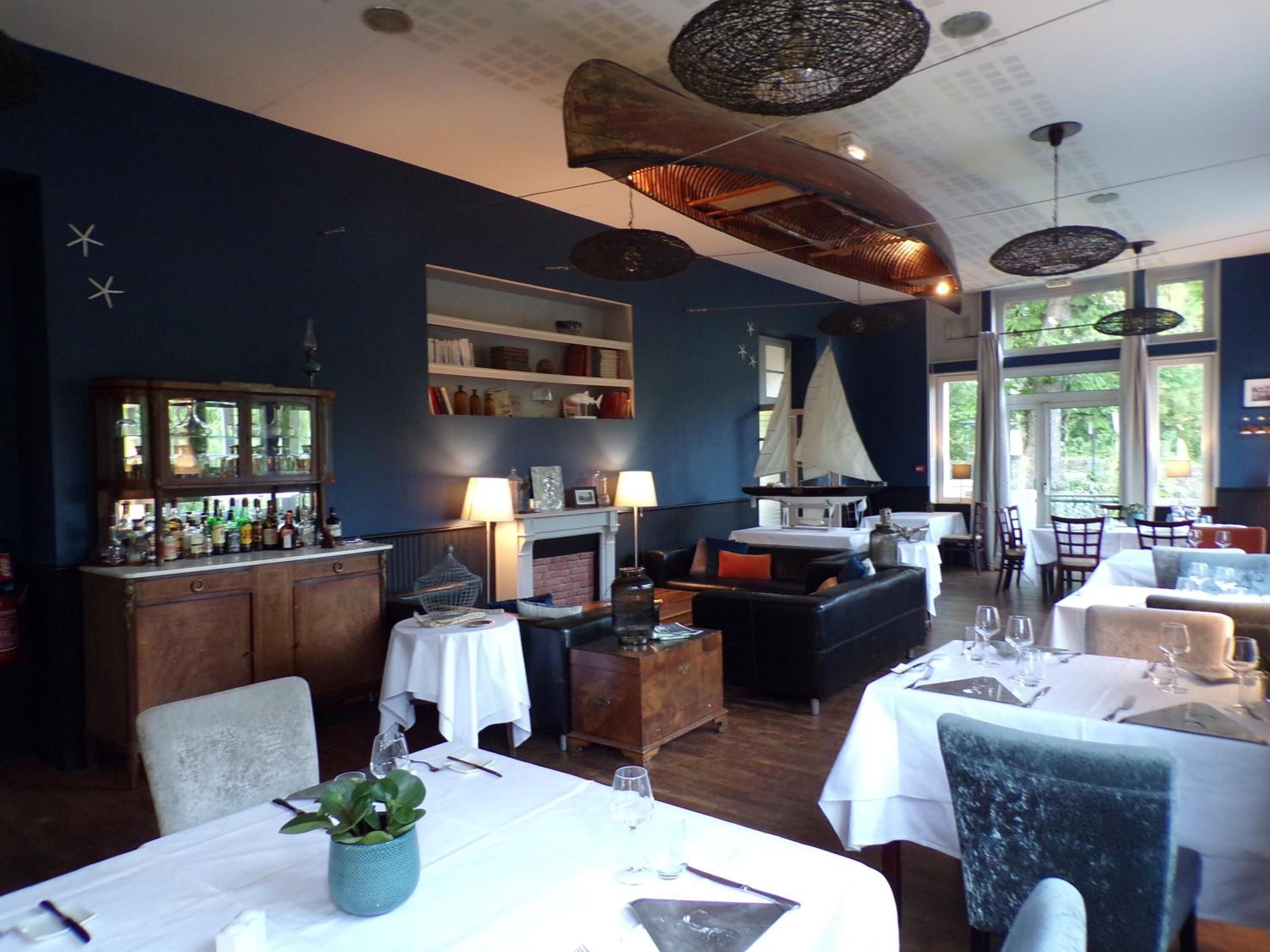 A dining area with a bar, tables set for dining, and a fireplace.