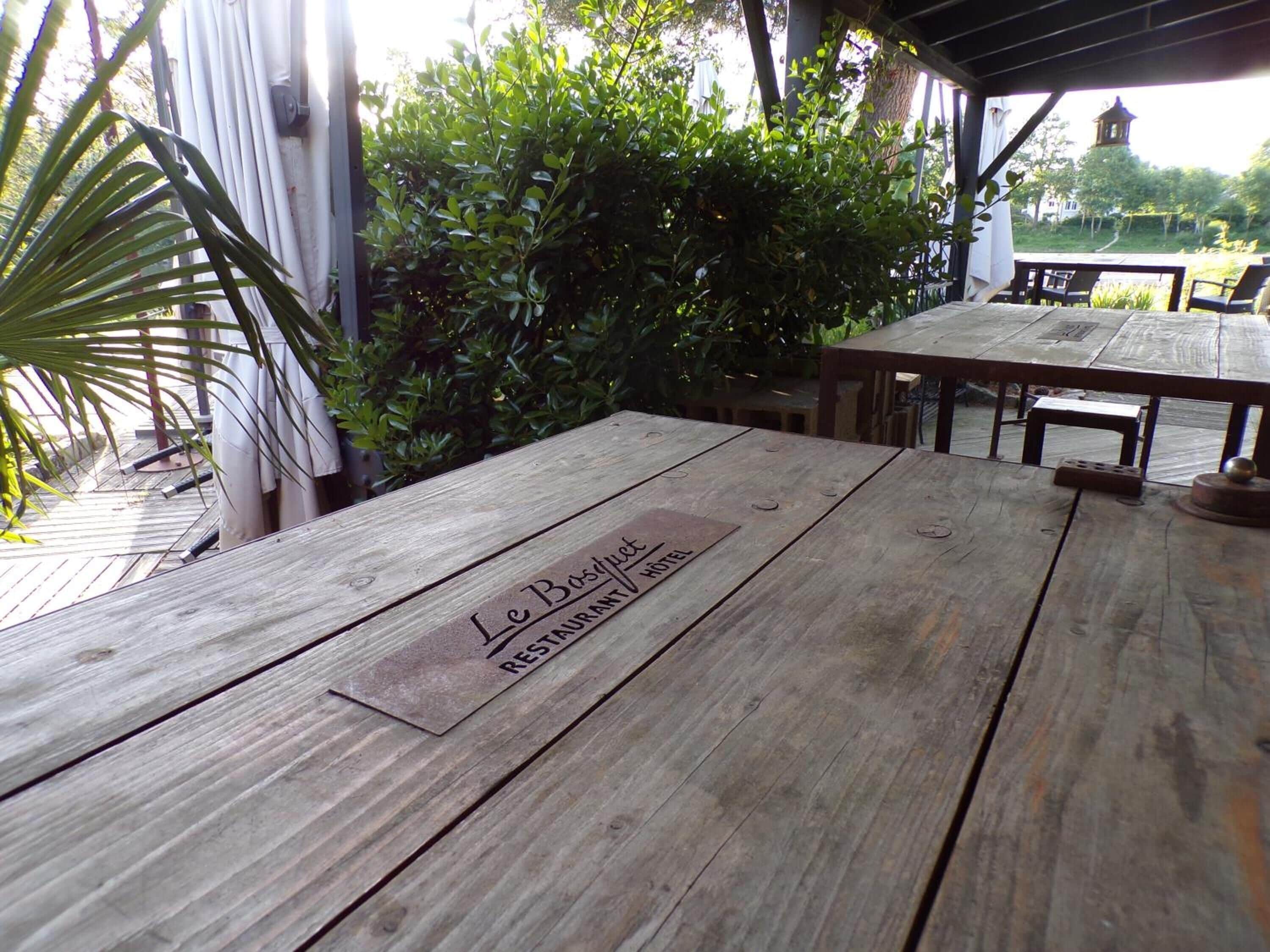 Una mesa de madera al aire libre con un letrero que dice 'Le Bosquet Restaurant'.